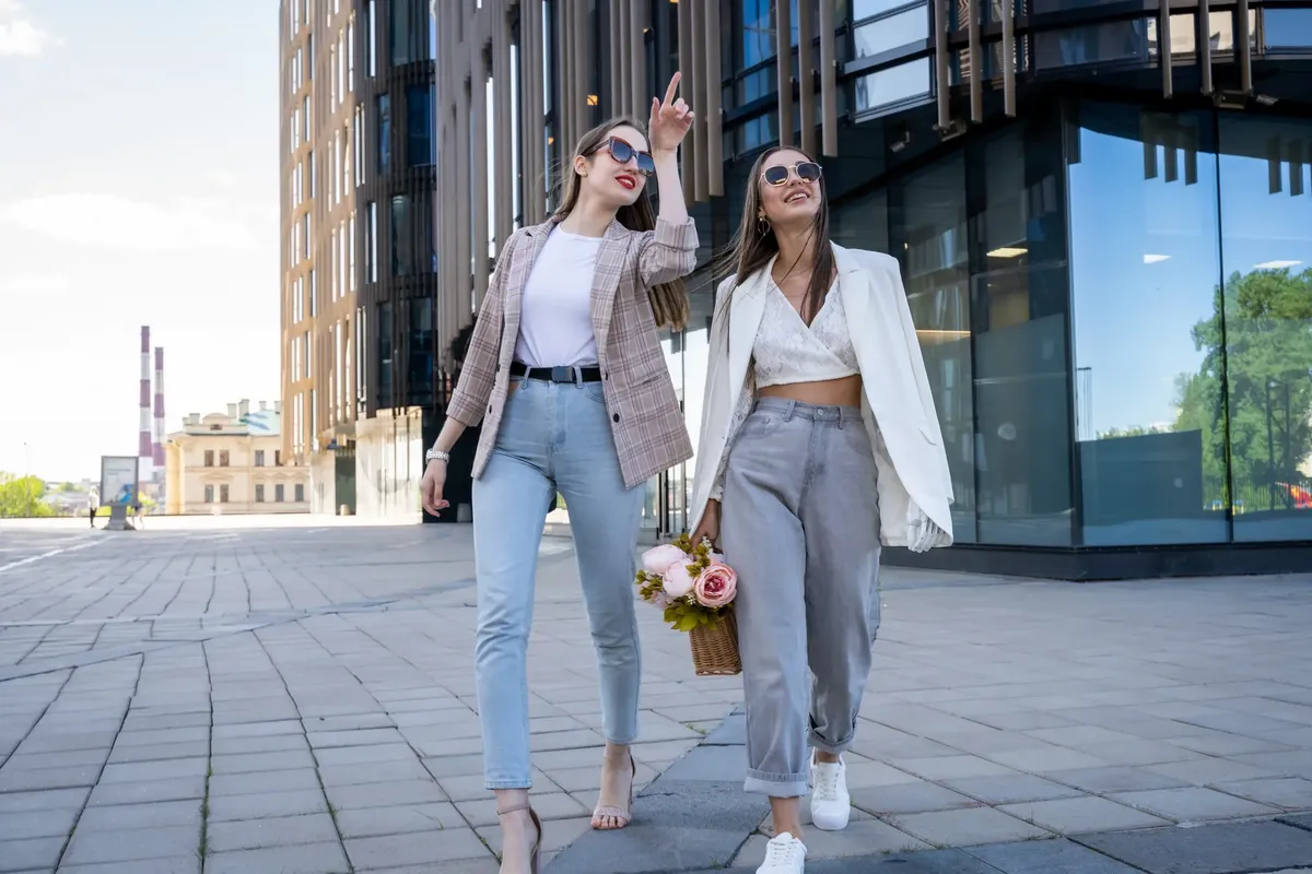 Two stylish women in sunglasses walking outdoors, embracing fashion trends.