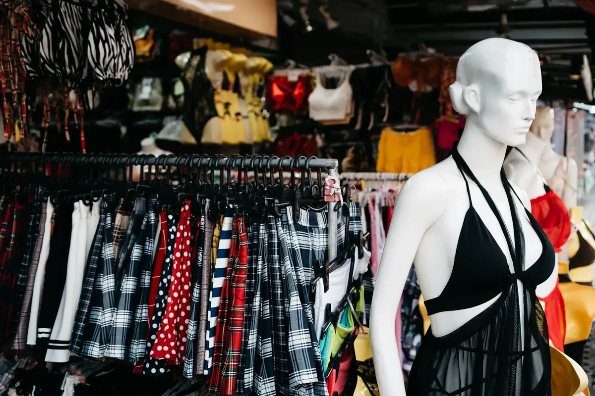 Vibrant market scene with a showcase of trendy clothing and a mannequin in an outdoor retail setting.