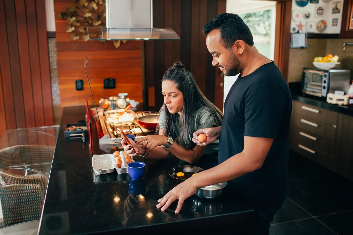 A couple cooking breakfast, sharing a moment at home in a sleek kitchen setting.